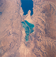 View of salt evaporation pans on the Dead Sea, taken in 1989 from the Space Shuttle Columbia. The southern half is now separated from the northern half at what used to be the Lisan Peninsula because of the fall of the level of Dead Sea. (Wikipedia)