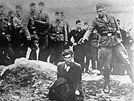 German soldiers of the Waffen-SS and the Reich Labor Service look on as a member of Einsatzgruppe D prepares to shoot a Ukrainian Jew kneeling on the edge of a mass grave filled with the bodies of previous victims